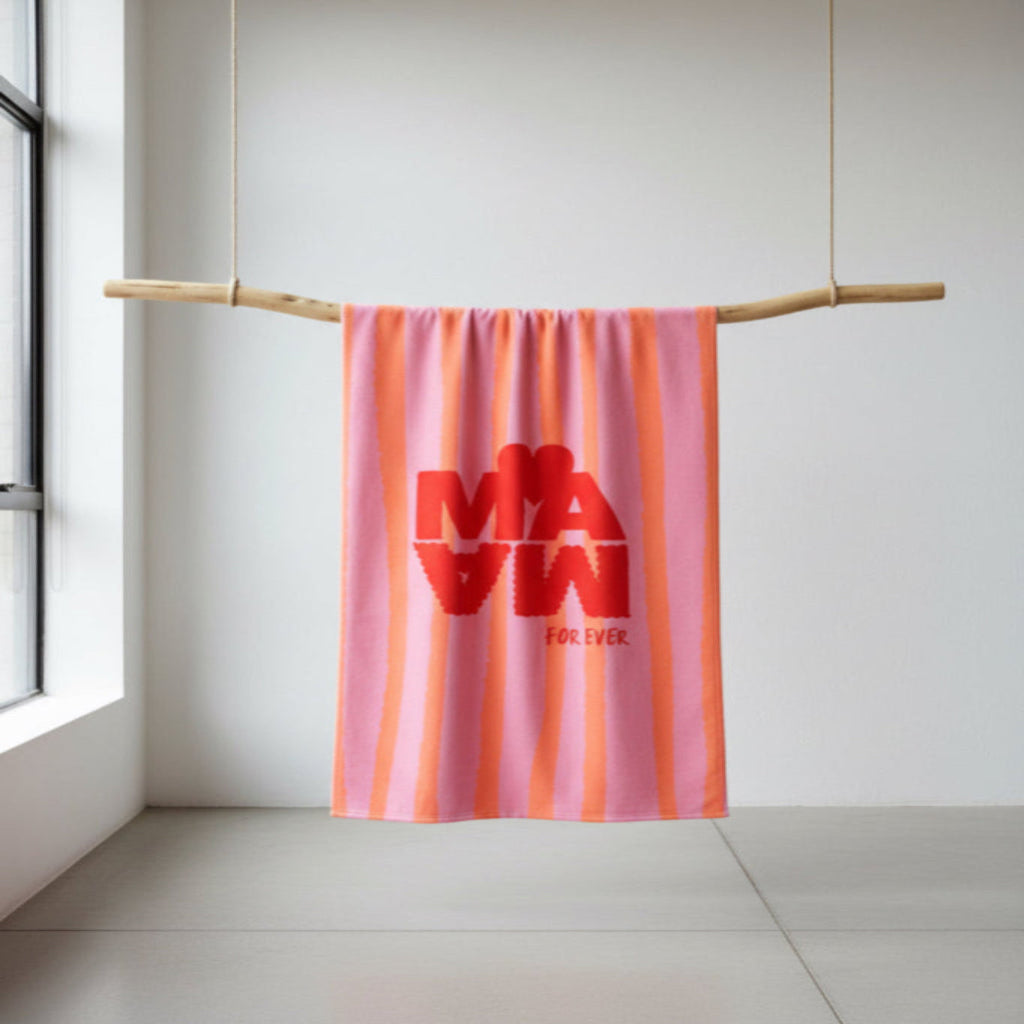 Serviette de plage rose à rayures verticales orange avec l'inscription "MAMA" en rouge et un cœur.