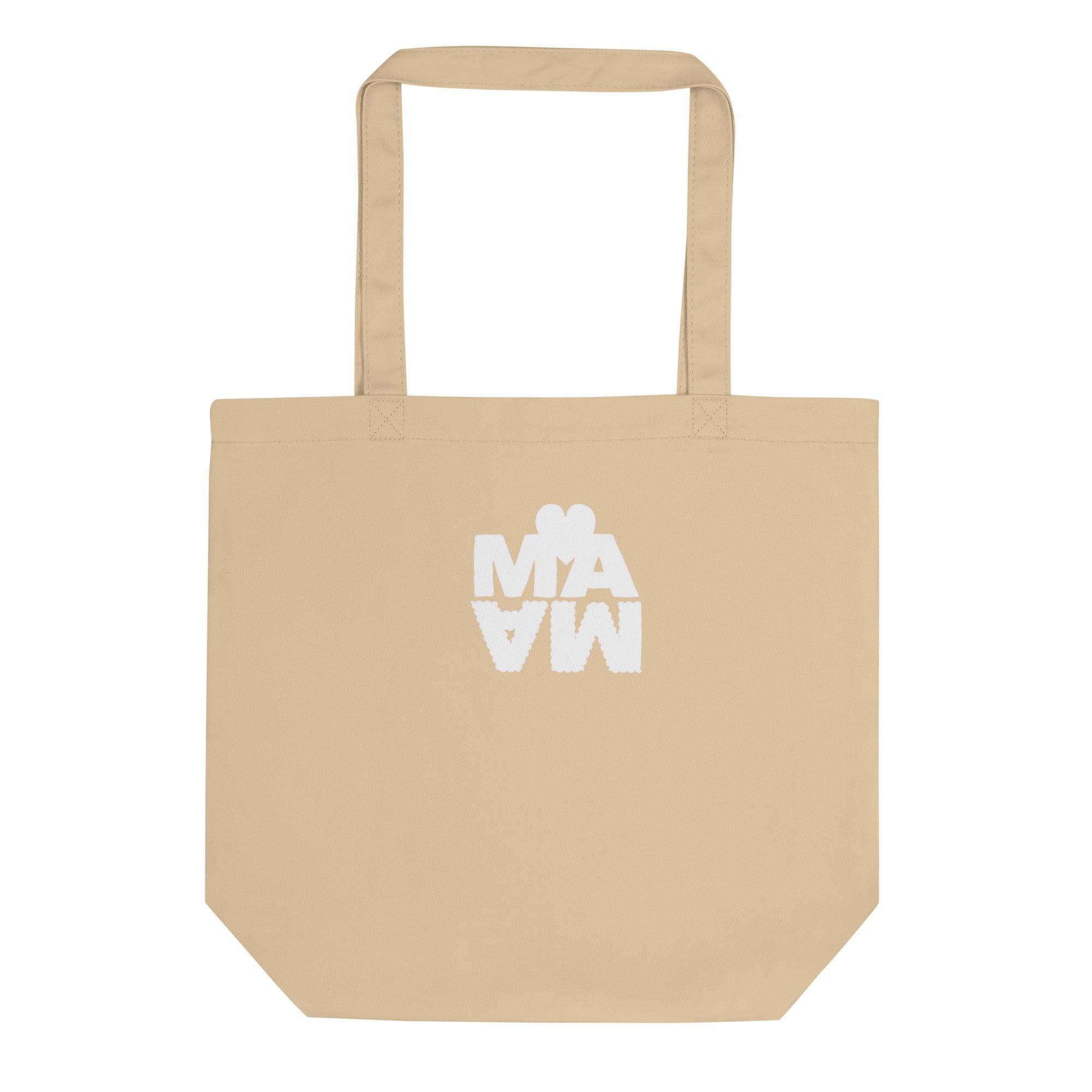 Sac cabas écologique de couleur beige sable avec l'inscription "MAMA" en lettres blanches épaisses. Le mot est stylisé avec un effet miroir vers le bas et surmonté d'un cœur blanc minimaliste. 
Design moderne et original sur fond blanc.