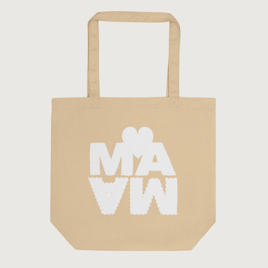 Sac cabas écologique de couleur beige sable avec l'inscription "MAMA" en lettres blanches épaisses. Le mot est stylisé avec un effet miroir vers le bas et surmonté d'un cœur blanc minimaliste. 
Design moderne et original sur fond blanc.